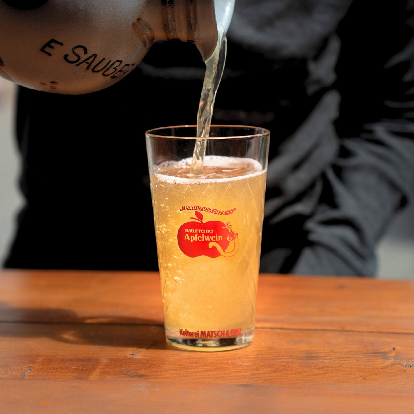 Matsch und Brei Apfelwein wird eingeschänkt aus Bembel draußen in der Sonne